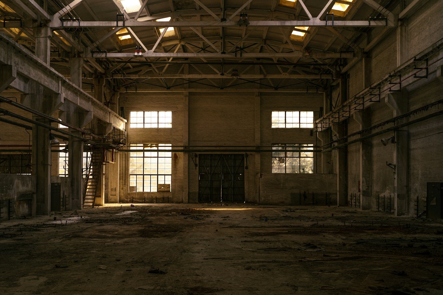 Interno di un capannone industriale con travature colonizzate dai piccioni